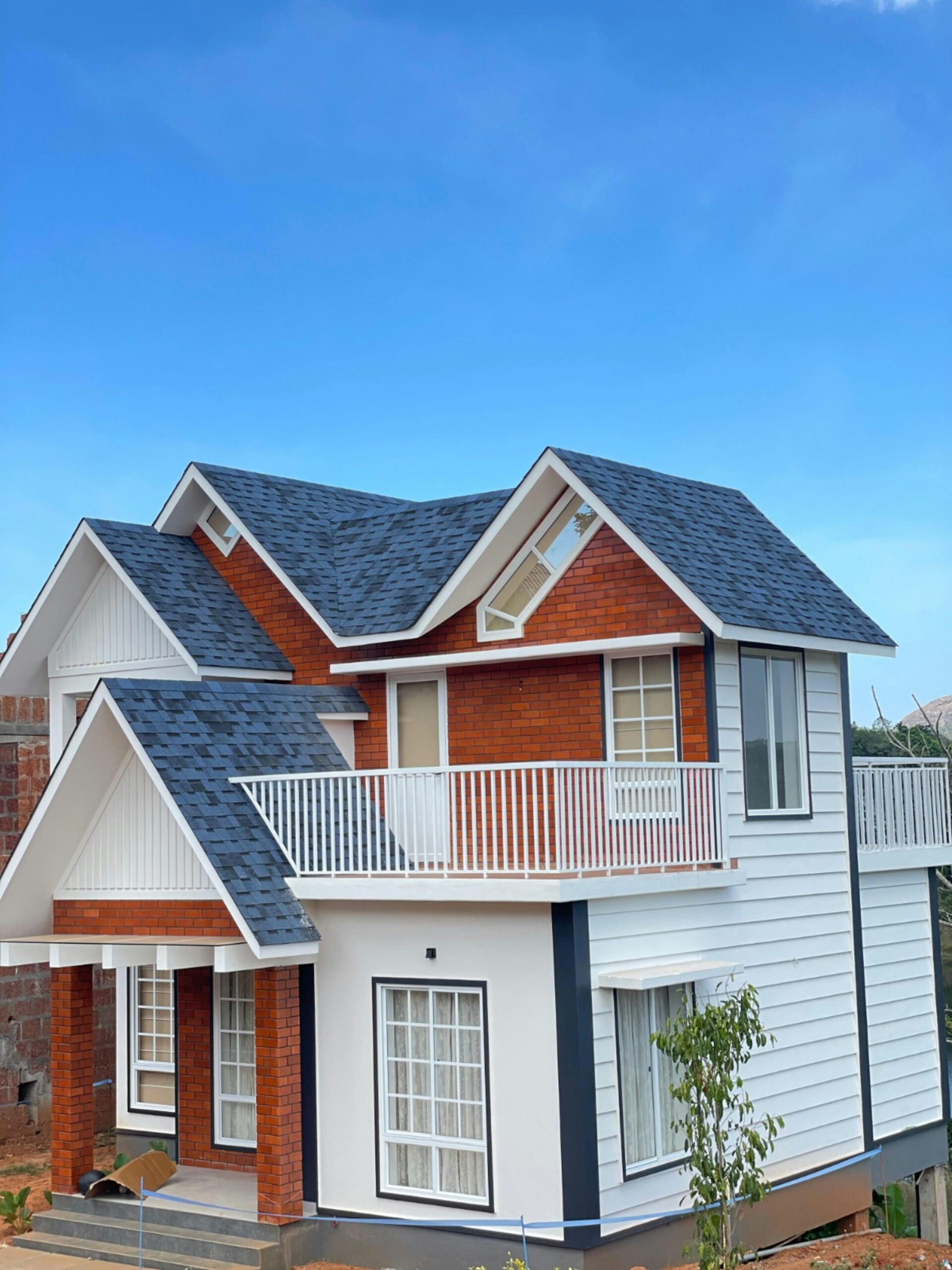 A modern two-story suburban house in Kottayam, India showcasing elegant architecture and a bright blue sky.